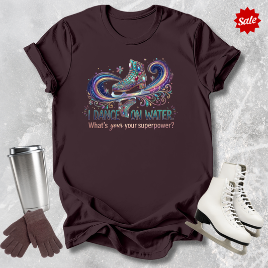Brown t-shirt with I dance on water ice skating design and accessories on a textured surface