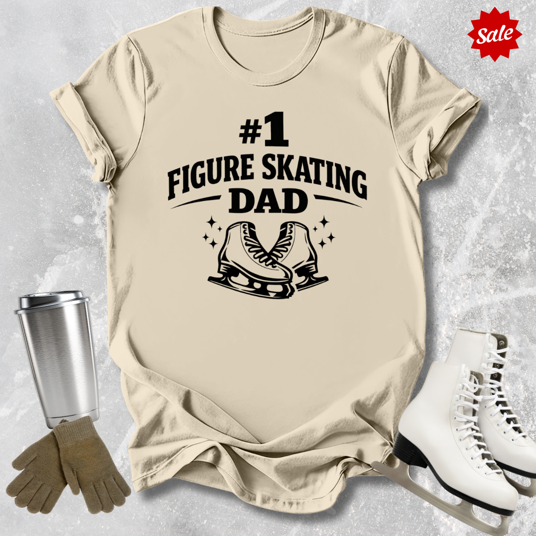 Beige t-shirt with '#1 Figure Skating Dad' text and graphics on a textured surface with ice skates and gloves.