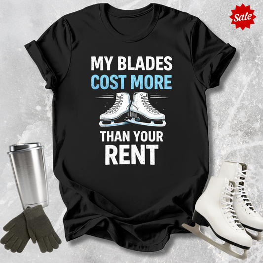 Black t-shirt with 'MY BLADES COST MORE THAN YOUR RENT' text, next to a silver tumbler, black gloves, and white figure skates on a textured gray background.