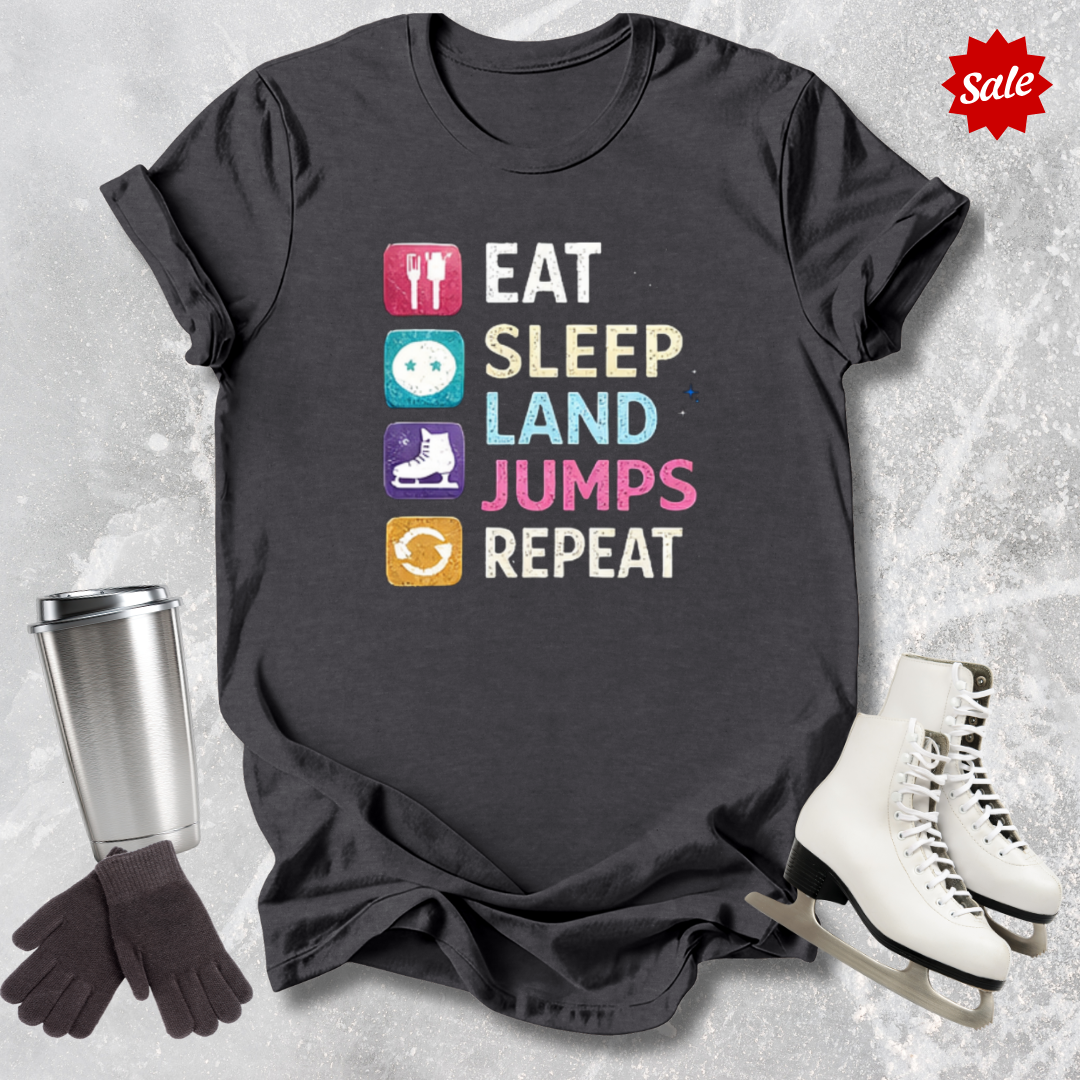 Black t-shirt with colorful text and graphics, surrounded by ice skates, gloves, and a tumbler on a textured surface.