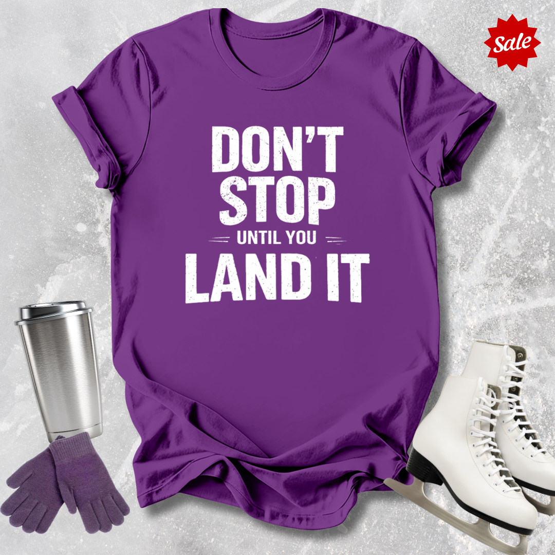 Purple t-shirt with motivational quote, silver tumbler, purple gloves, and white skates on a textured gray background.