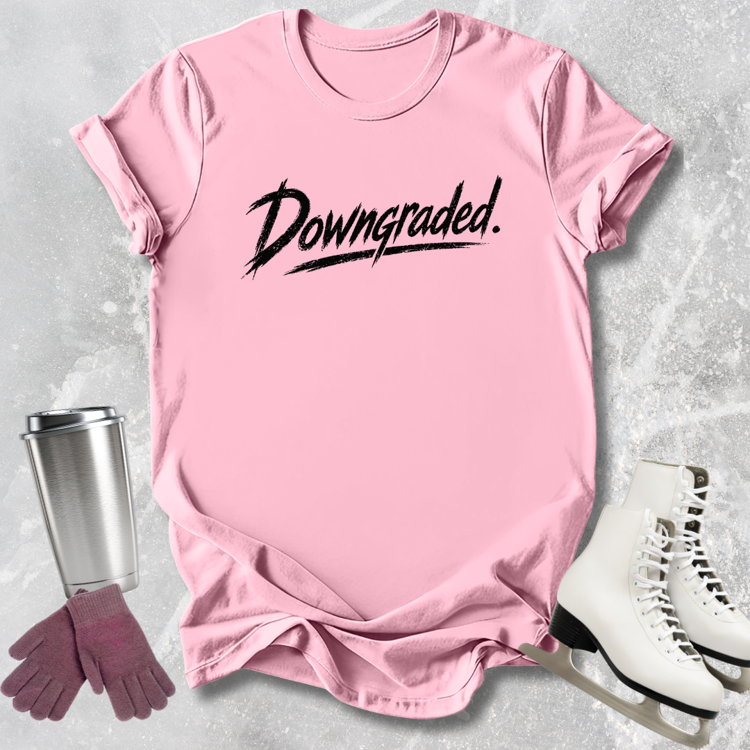 Pink t-shirt with 'Downgraded' text, silver tumbler, pink gloves, and white skates on a gray textured background