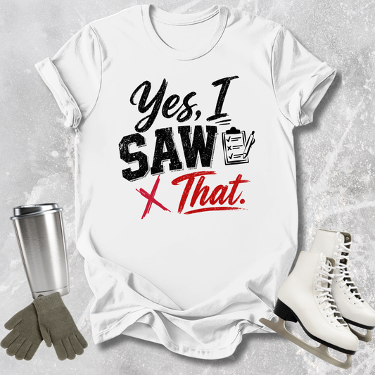White t-shirt with 'Yes, I Saw That' text, next to a silver tumbler, gray gloves, and white skates on a textured gray background.