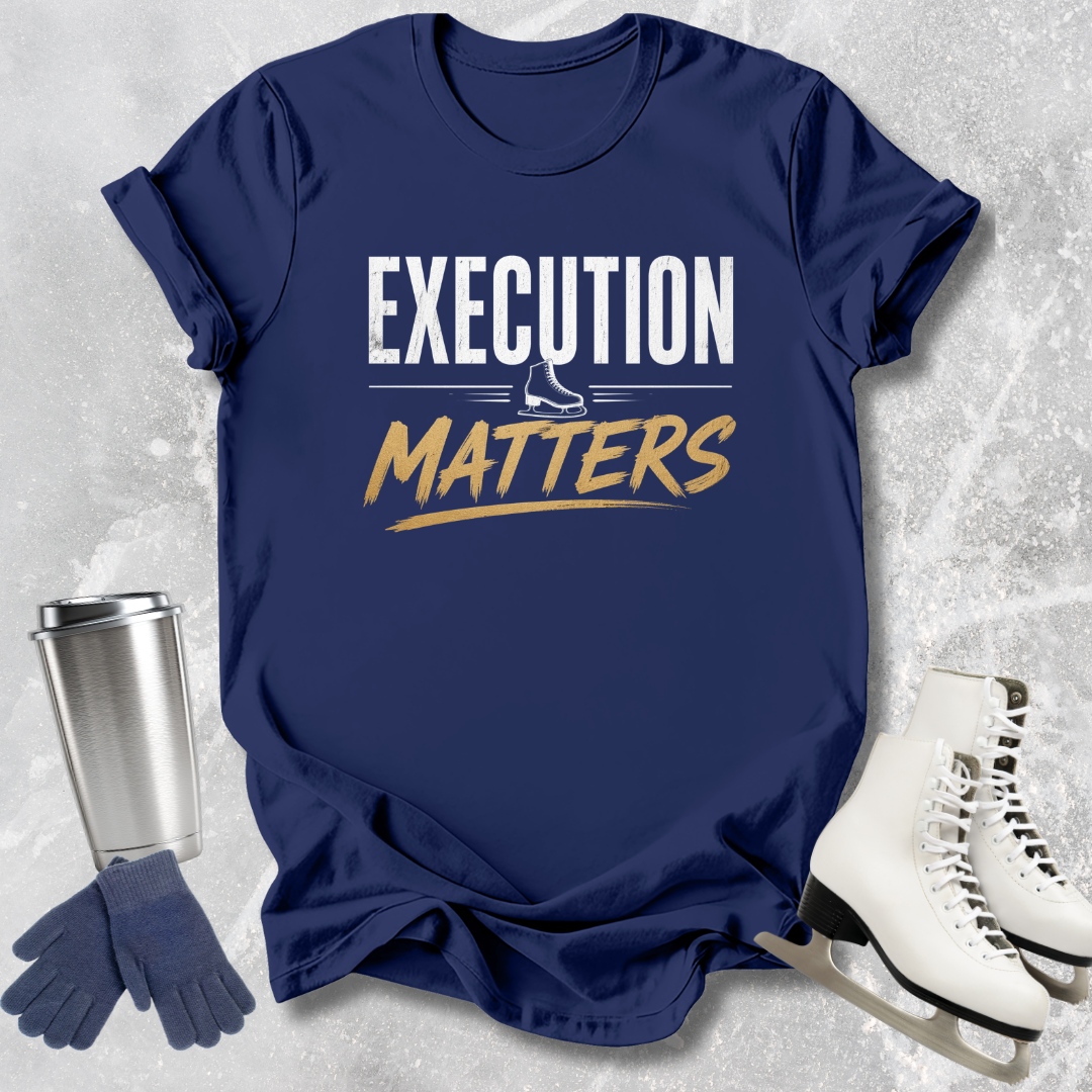 Navy blue t-shirt with 'EXECUTION MATTERS' text, next to a silver tumbler, gloves, and white skates on a textured gray background.