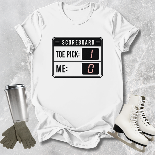 White t-shirt with scoreboard design, surrounded by ice skates, gloves, and a tumbler on a textured surface.