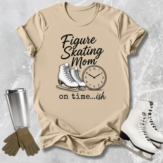 Beige t-shirt with figure skating mom graphic and accessories on a textured surface