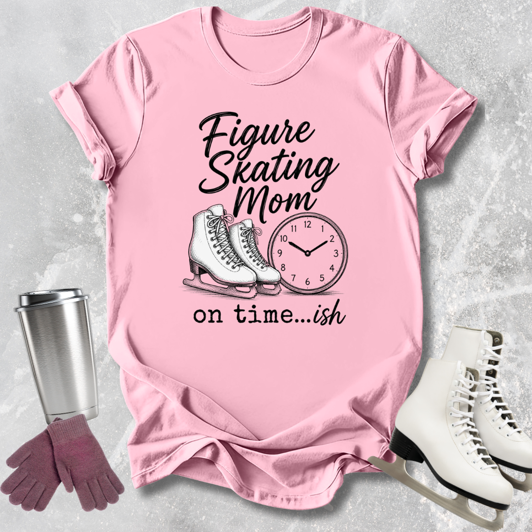 Pink t-shirt with figure skating mom graphic on a textured surface with skates and gloves.