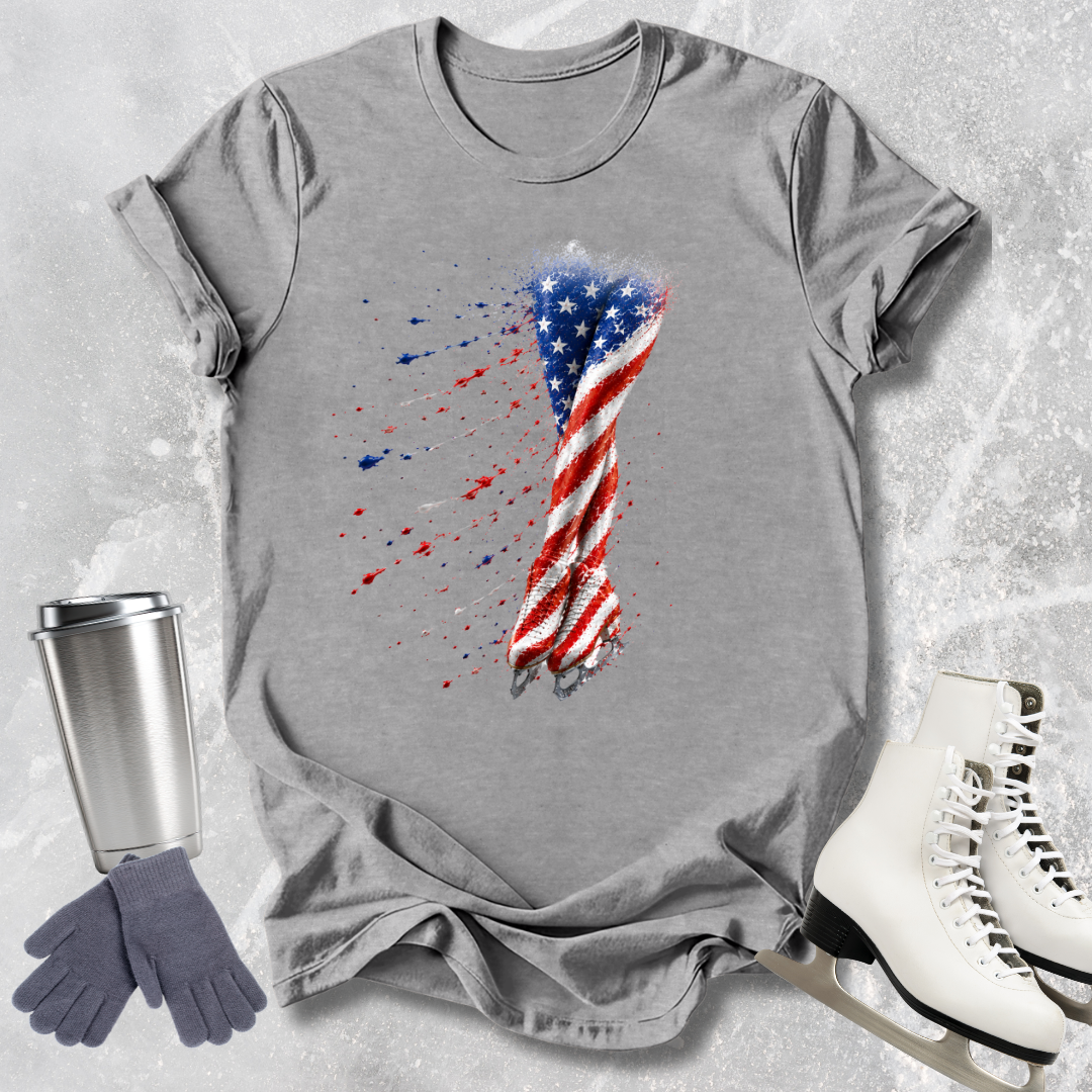 Gray t-shirt with American flag design, silver tumbler, gray gloves, and white skates on a textured surface