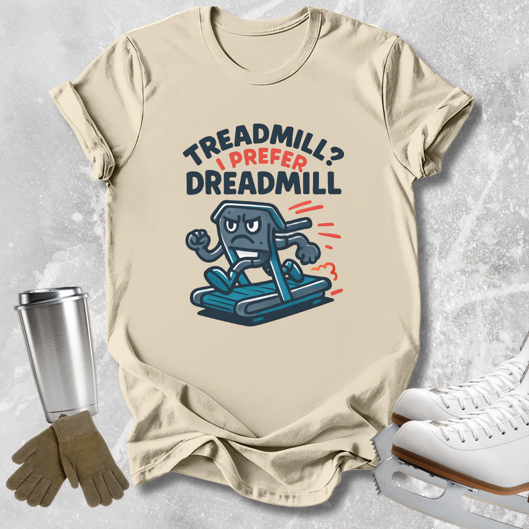 A beige graphic t-shirt laid flat on a light gray textured background, styled with a stainless steel tumbler, gloves, and ice skates. The t-shirt features a cartoon graphic of a blue treadmill character with the text 'TREADMILL? I PREFER DREADMILL' in dark blue and red.