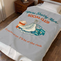 A light gray bedding set, including a comforter and matching pillowcase, displayed on a bed in a bedroom. The comforter features a graphic design with the text 'Figure Skating Mom SOCIAL CLUB' and 'if you need me, I'll be at the rink' in teal and orange lettering, accompanied by illustrations of ice skates, a sweater, and a hot coffee cup.