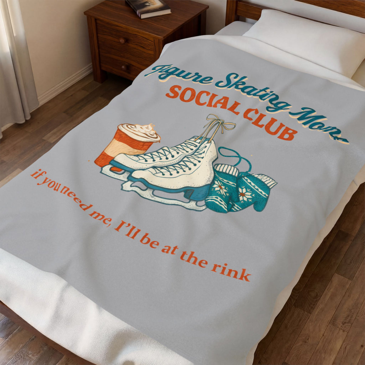 A light gray bedding set, including a comforter and matching pillowcase, displayed on a bed in a bedroom. The comforter features a graphic design with the text 'Figure Skating Mom SOCIAL CLUB' and 'if you need me, I'll be at the rink' in teal and orange lettering, accompanied by illustrations of ice skates, a sweater, and a hot coffee cup.