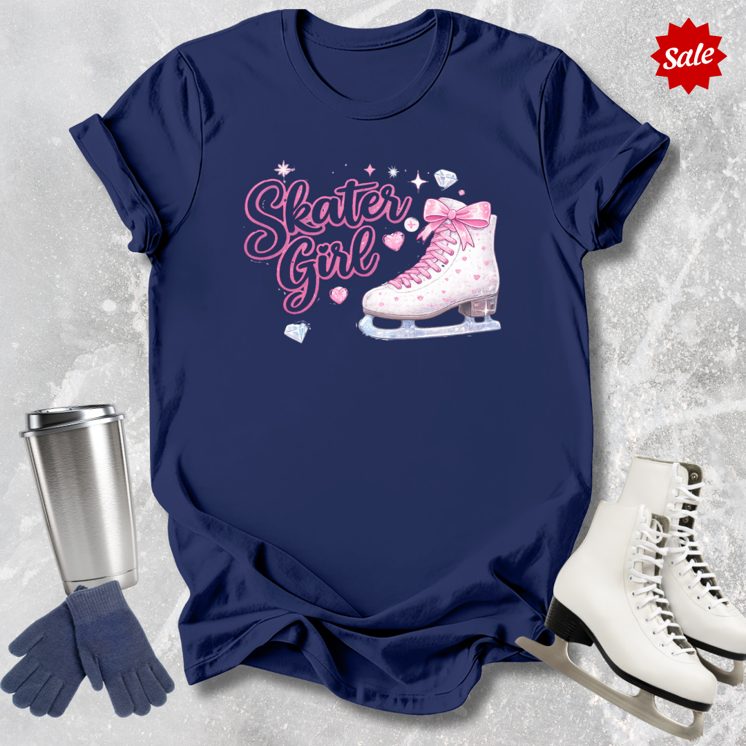 Navy blue t-shirt with 'Skater Girl' graphic, silver tumbler, gloves, and ice skates on a textured gray background.