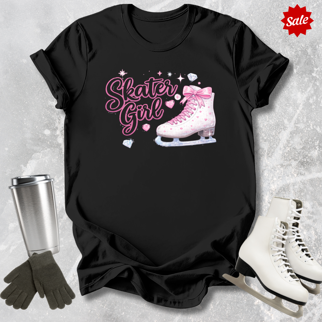 Black t-shirt with 'Skater Girl' design featuring a pink溜冰鞋 and heart shapes, surrounded by ice skates and gloves on a textured gray background.