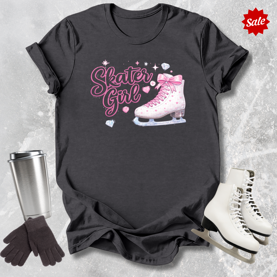 Black t-shirt with 'Skater Girl' graphic, silver tumbler, black gloves, and white ice skates on a textured gray background.
