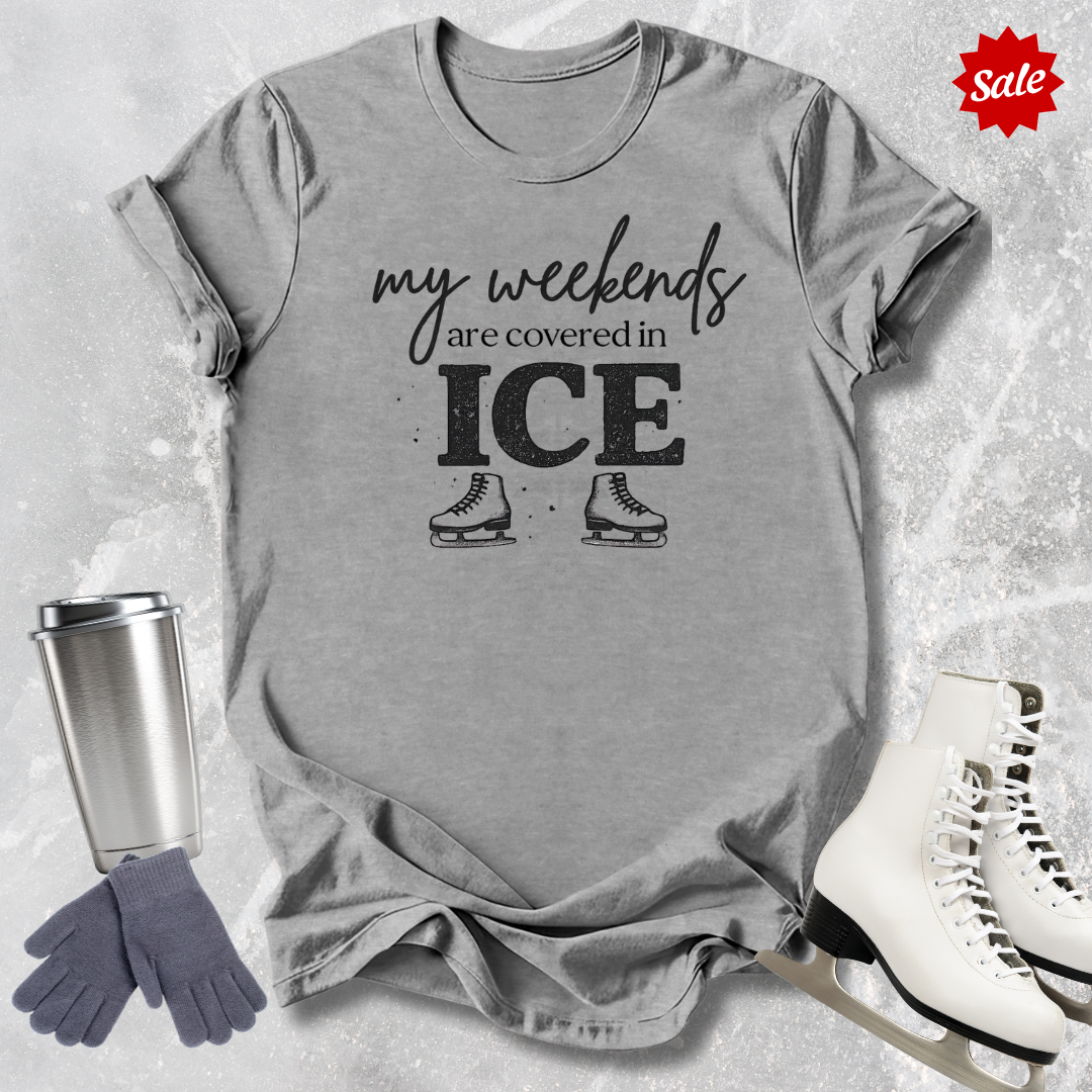 Gray t-shirt with 'my weekends are covered in ICE' text and ice skates, next to a silver tumbler, gray gloves, and white ice skates on a light gray background.