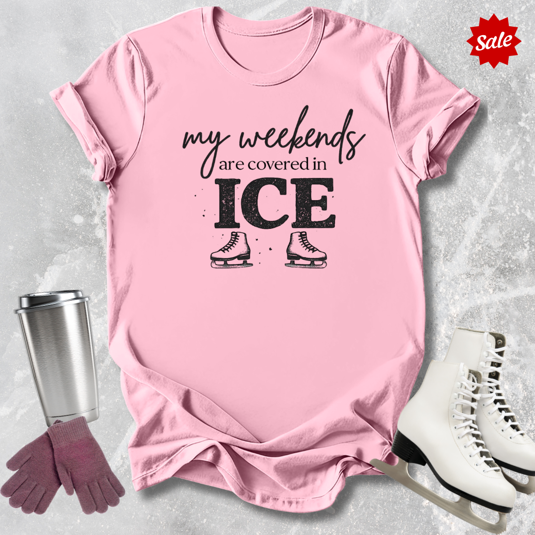 Pink t-shirt with 'my weekends are covered in ICE' text, surrounded by ice skates, gloves, and a tumbler on a light gray background.