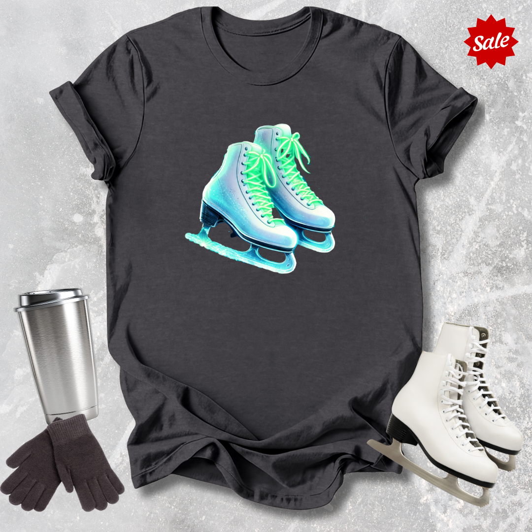 Black t-shirt with neon  ice skate design   for figure skaters, silver tumbler, black gloves, and white ice skates on a textured gray background.