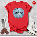 Red t-shirt with 'Survivor' graphic  for figure skaters, figure skates, gloves, and a cup on a textured gray background.