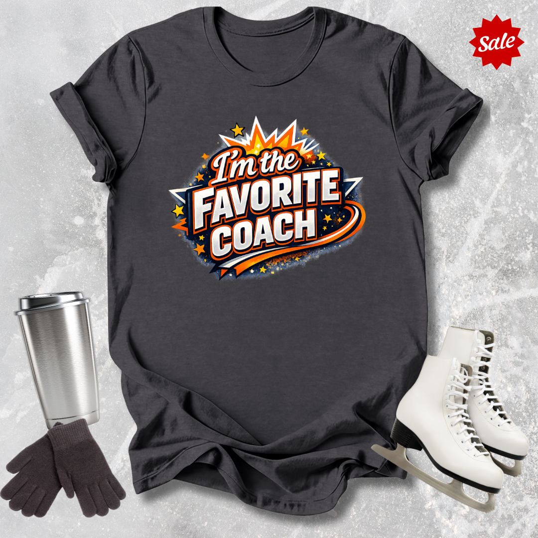 heather gray  t-shirt with 'I'm the Favorite Coach' design  for figure skating coaches, surrounded by a silver tumbler, black gloves, and white skates on a textured gray background.