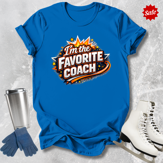 Blue t-shirt with 'I'm the Favorite Coach'  for figure skating coaches design, silver tumbler, blue gloves, and white skates on a textured gray background.