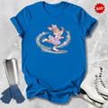 Blue t-shirt with a cartoon a figure skating Easter bunny design, next to a silver tumbler, blue gloves, and white ice skates on a textured gray background.