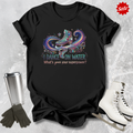Black t-shirt with ice skating I dance on water design and text, surrounded by ice skates and a tumbler on a textured gray background.