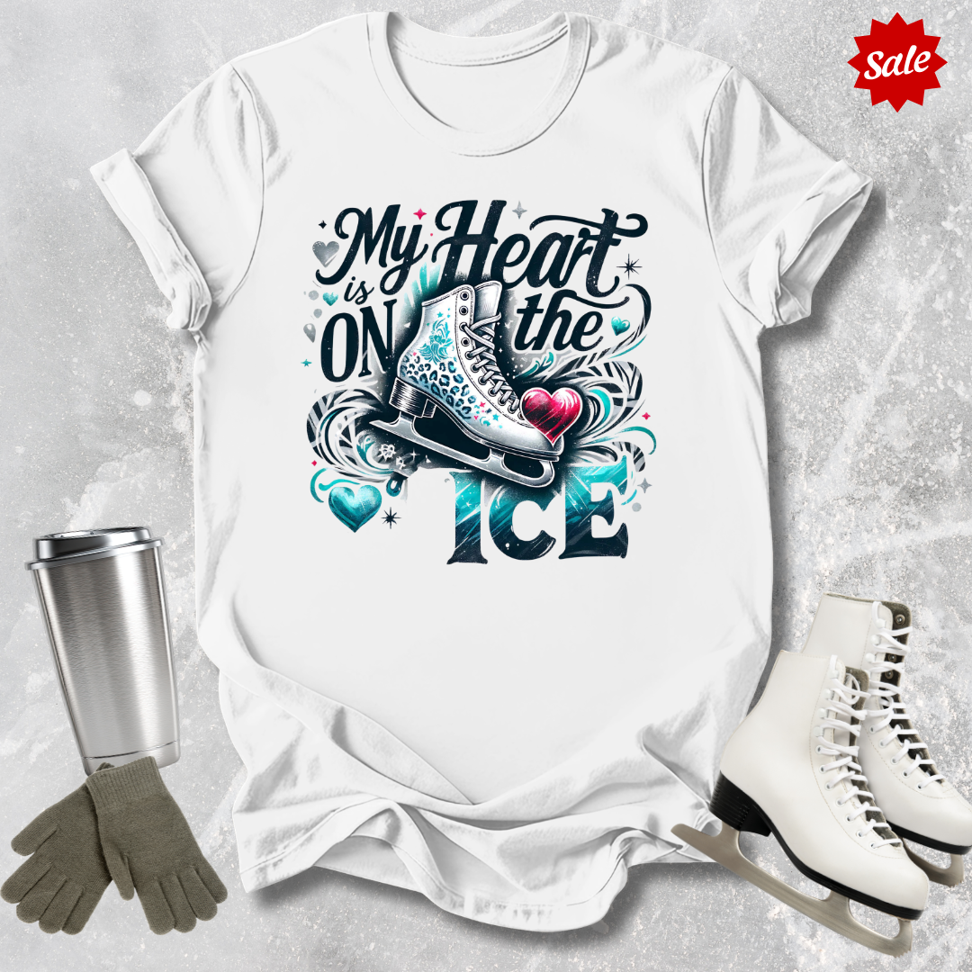 White t-shirt with 'My Heart is on the Ice' design, surrounded by ice skates and a tumbler on a textured gray background.