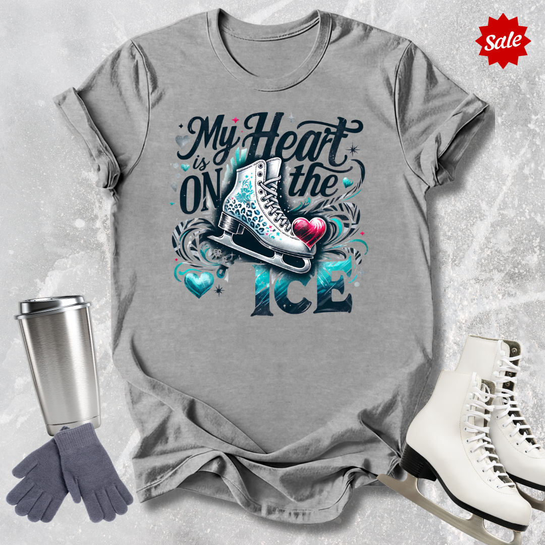 Gray t-shirt with ice skating design with my heart is on the ice text, silver tumbler, gray gloves, and white ice skates on a textured background.