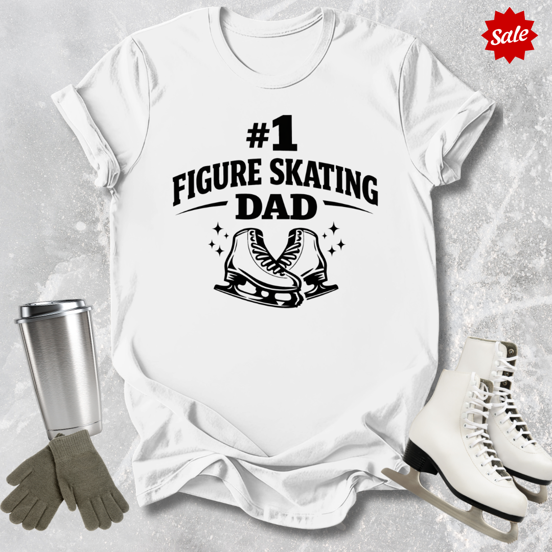 White t-shirt with '#1 Figure Skating Dad' text and graphics, surrounded by figure skating accessories on a textured surface.