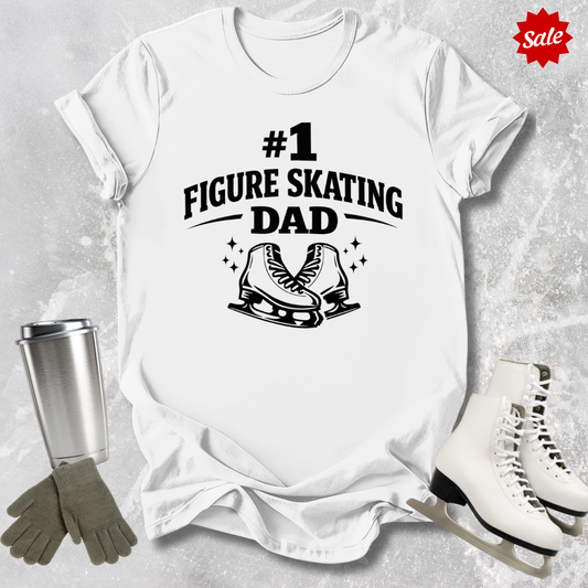 White t-shirt with '#1 Figure Skating Dad' text and graphics, surrounded by figure skating accessories on a textured surface.