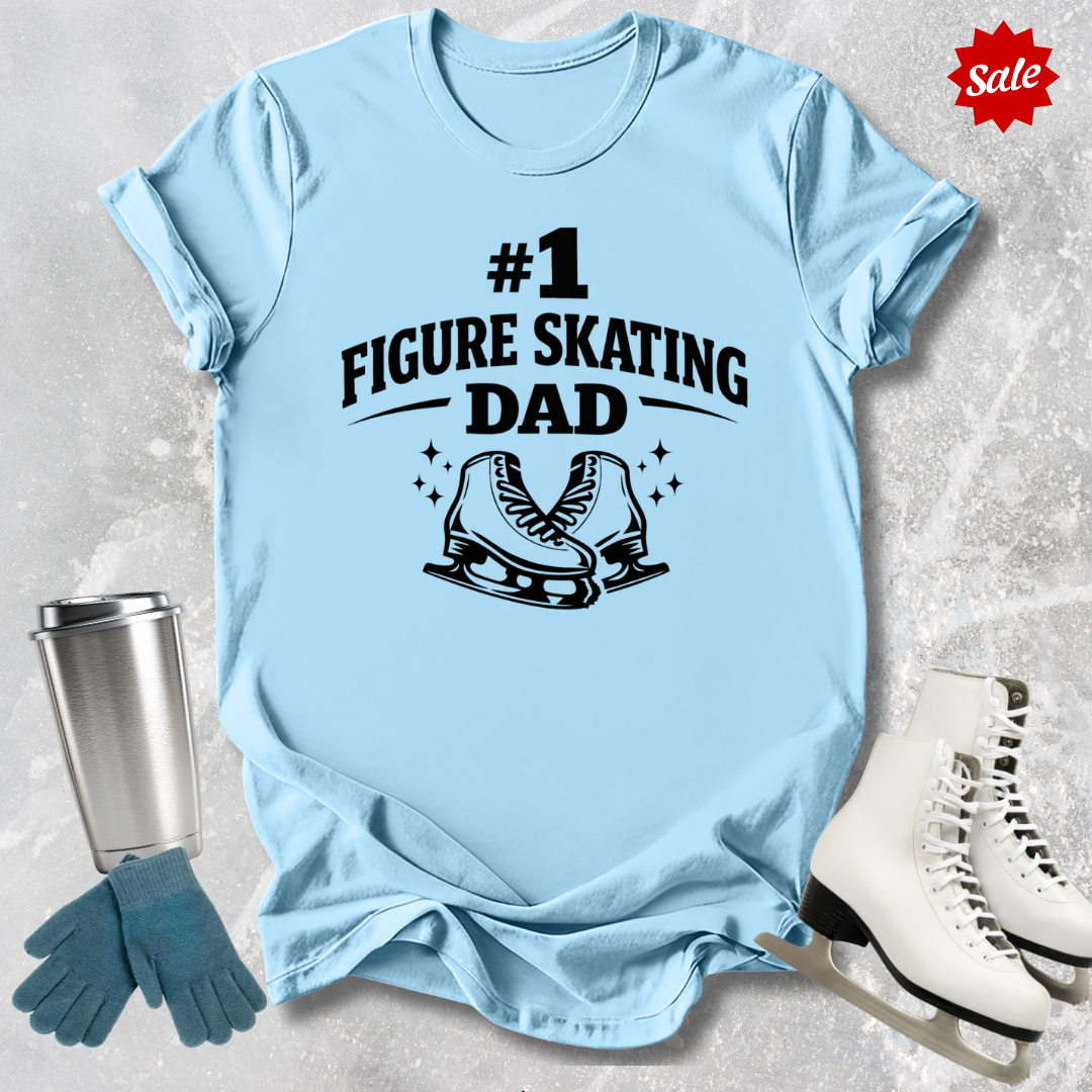Light blue t-shirt with '#1 Figure Skating Dad' text and ice skate graphics, surrounded by ice skates and a tumbler on a textured surface.