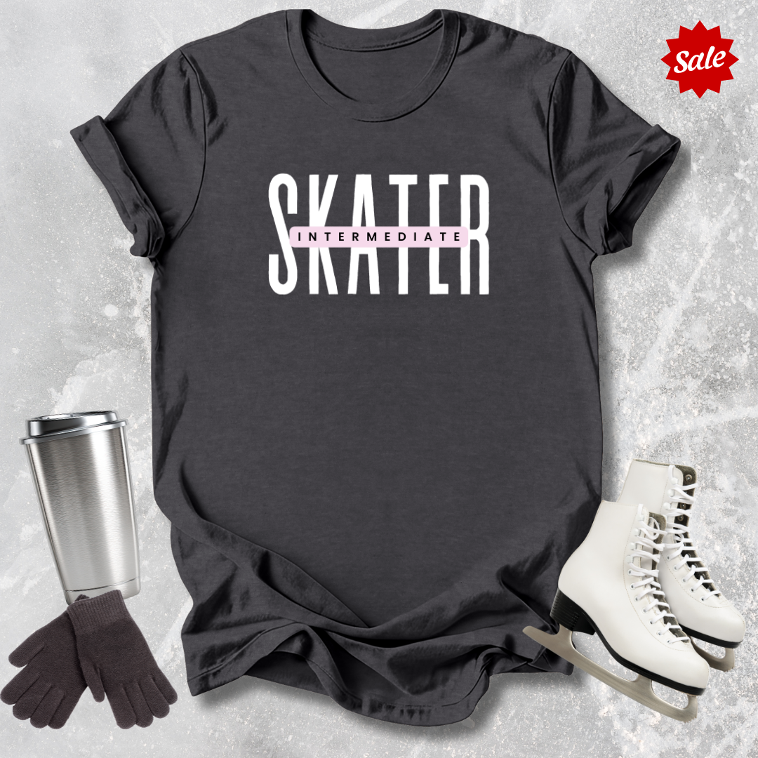 Black t-shirt with 'SKATER INTERMEDIATE' text, silver tumbler, black gloves, and white skates on a textured gray background.