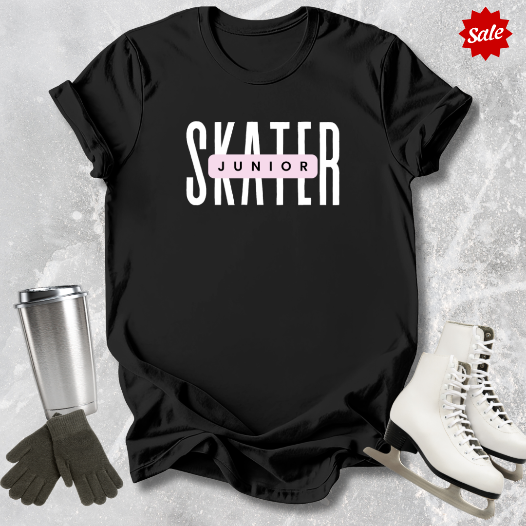 Black t-shirt with 'SKATER JUNIOR' text, silver tumbler, black gloves, and white ice skates on a gray textured background.