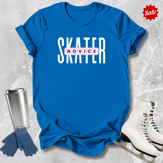 Blue t-shirt with 'SKATER JUNIOR' text, silver tumbler, blue gloves, and white ice skates on a textured gray background.