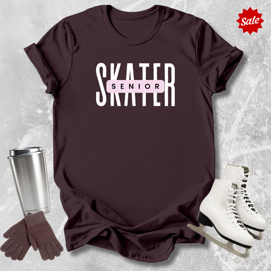 Maroon t-shirt with 'SKATER' text, silver tumbler, brown gloves, and white skates on a textured gray background.