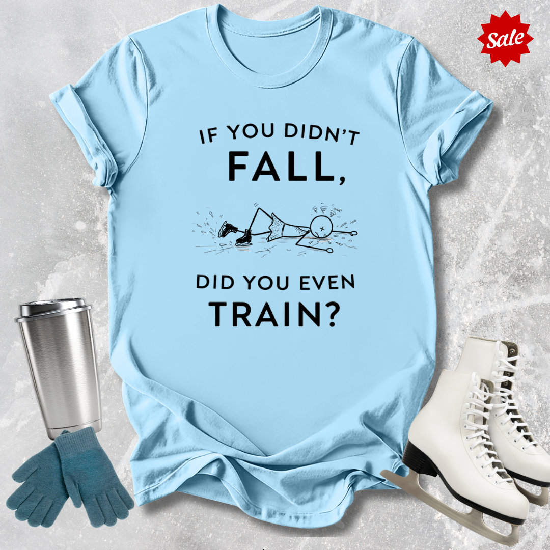 Light blue t-shirt with humorous graphic and  if you didn't fall did you even train text, placed on a textured surface with accessories like gloves and skates.