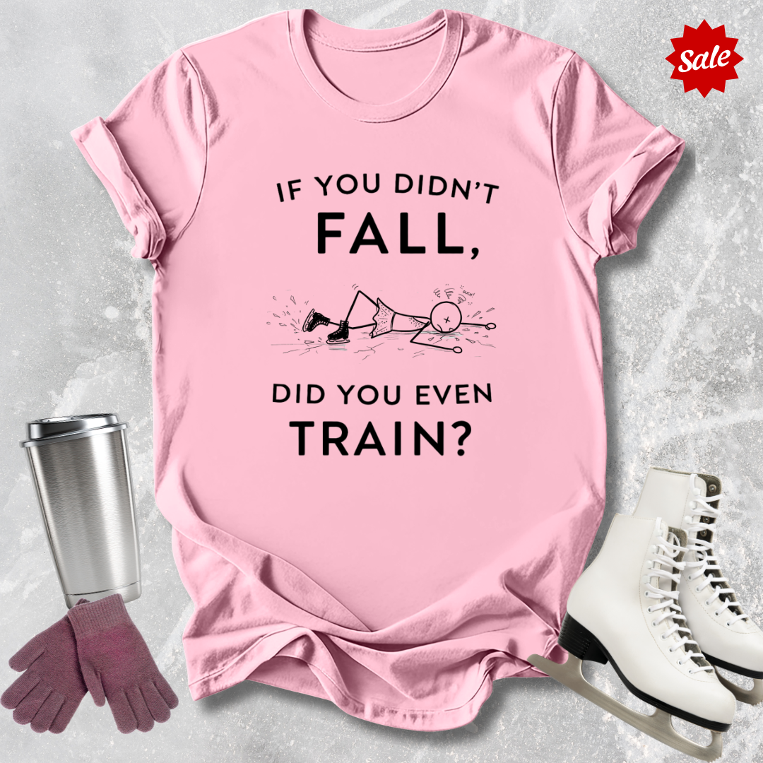 Pink t-shirt with humorous  if you didn't fall did you even train text, and graphics, placed on a textured surface with a tumbler, gloves, and skates.