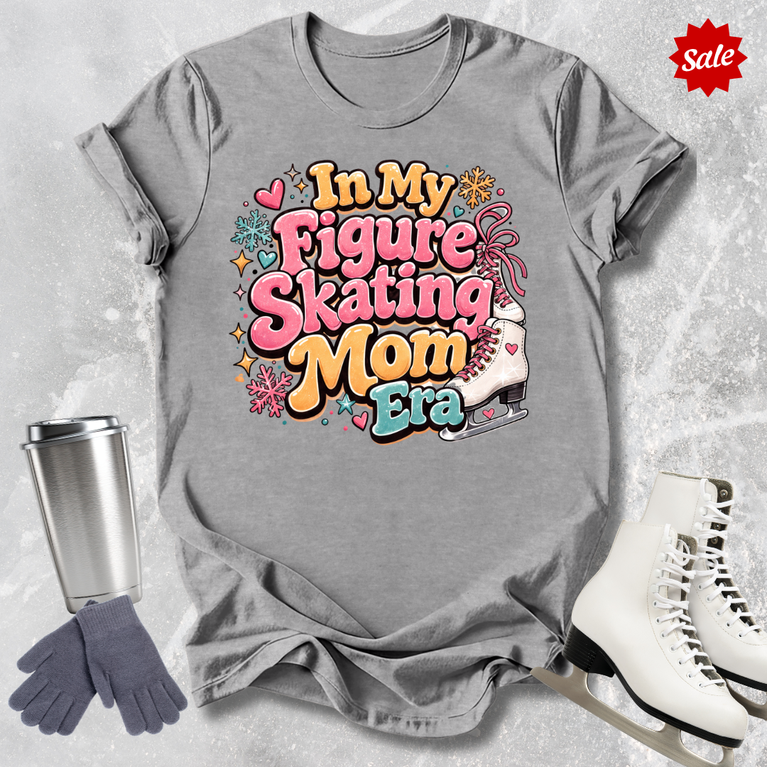 Gray t-shirt with colorful text 'In My Figure Skating Mom Era' on a textured gray background with ice skates and gloves.
