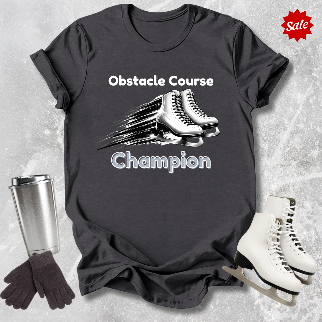 Black t-shirt with ice skates and 'Obstacle Course Champion' text, surrounded by ice skates and a travel mug on a textured surface.