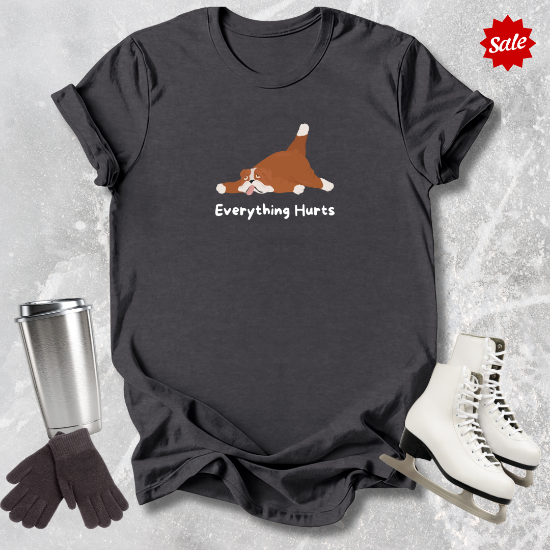Black t-shirt with a graphic and text 'Everything Hurts', placed on a textured surface with a silver tumbler, black gloves, and white skates.