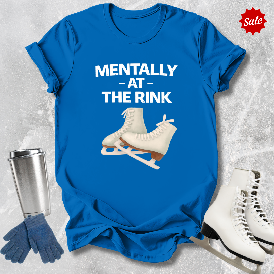 Blue t-shirt with ice skate graphic and text 'Mentally at the rink' on a textured gray background.