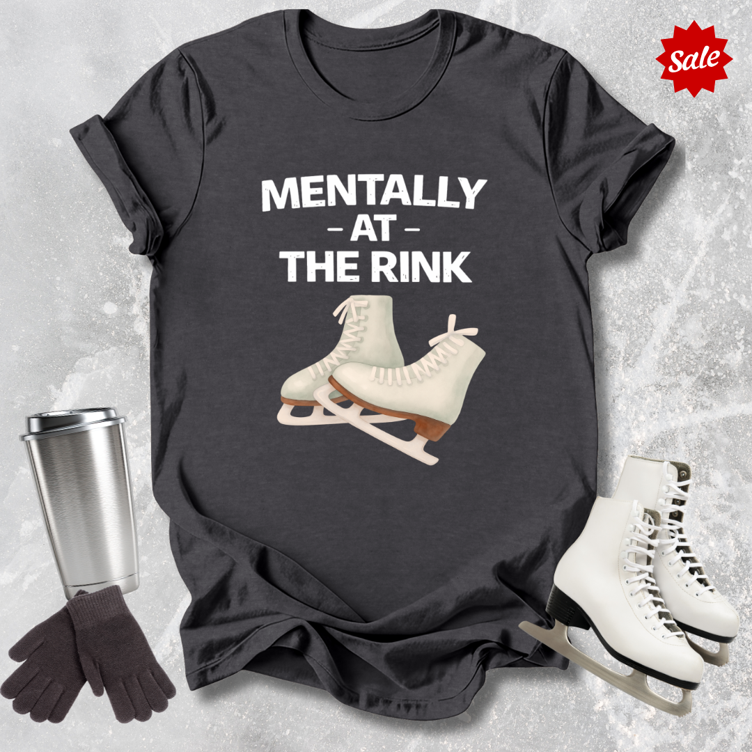 Black t-shirt with ice skates and text 'Mentally at the Rink' on a textured surface with accessories.