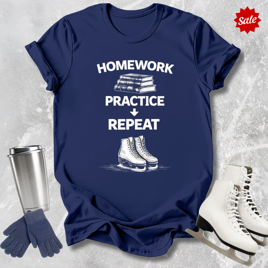 Navy t-shirt with 'Homework, practice, repeat' text, next to a silver tumbler, black gloves, and white figure skates on a textured gray background.