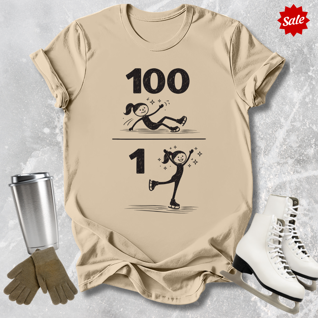 Beige t-shirt with '100 Figure skating falls and 1 landed jump' text, next to a silver tumbler, black gloves, and white figure skates on a textured gray background.