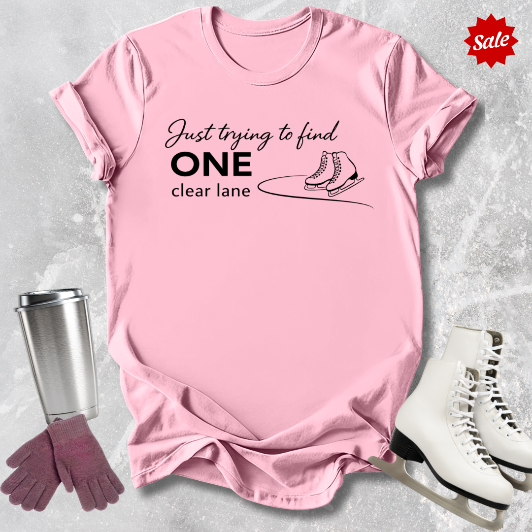 Pink t-shirt with humorous text, surrounded by ice skates, gloves, and a tumbler on a light gray background.