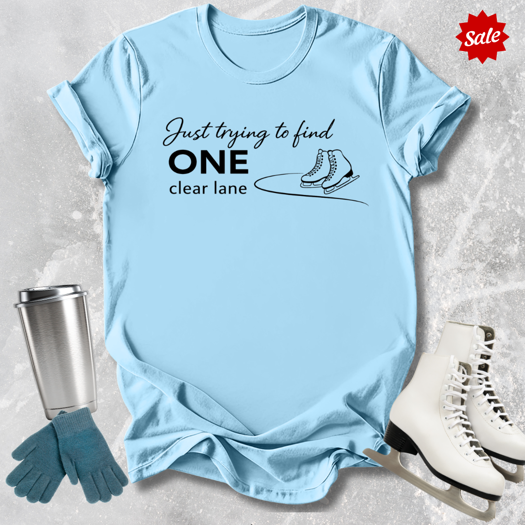 Light blue t-shirt with humorous text design, placed on a textured surface with ice skates and a tumbler for context.