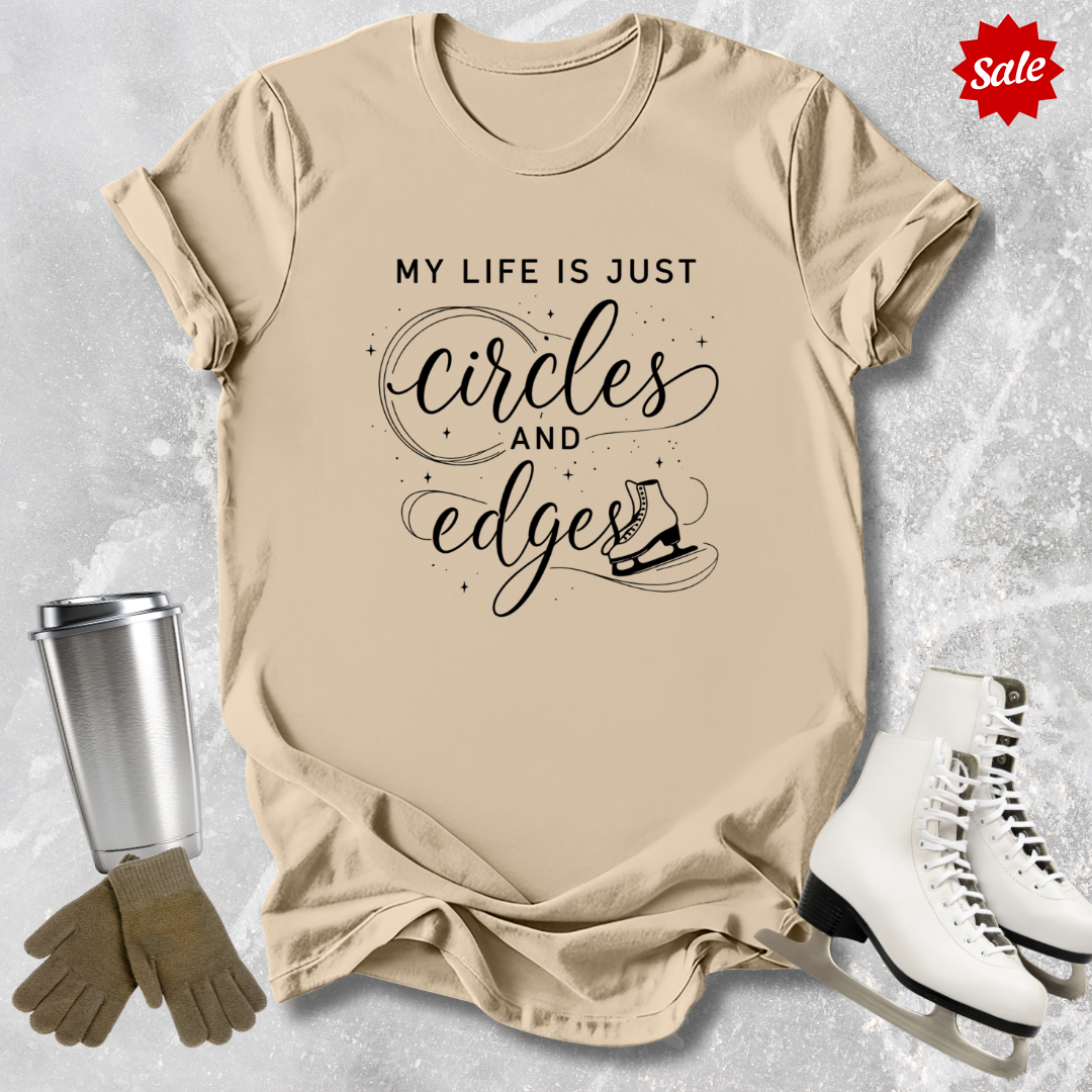 Beige t-shirt with My Life is just circles and edges Figure Skating text, silver tumbler, brown gloves, and white skates on a light gray background.