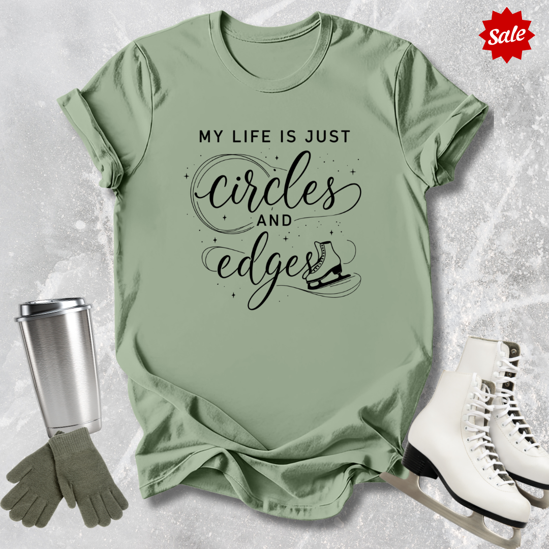 Green t-shirt with My Life is just circles and edges Figure Skating text, silver tumbler, green gloves, and white skates on a textured surface.