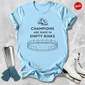 Light blue t-shirt with a figure skating design and Champions are Made in Empty Rinks text, surrounded by ice skates and a tumbler on a textured surface.