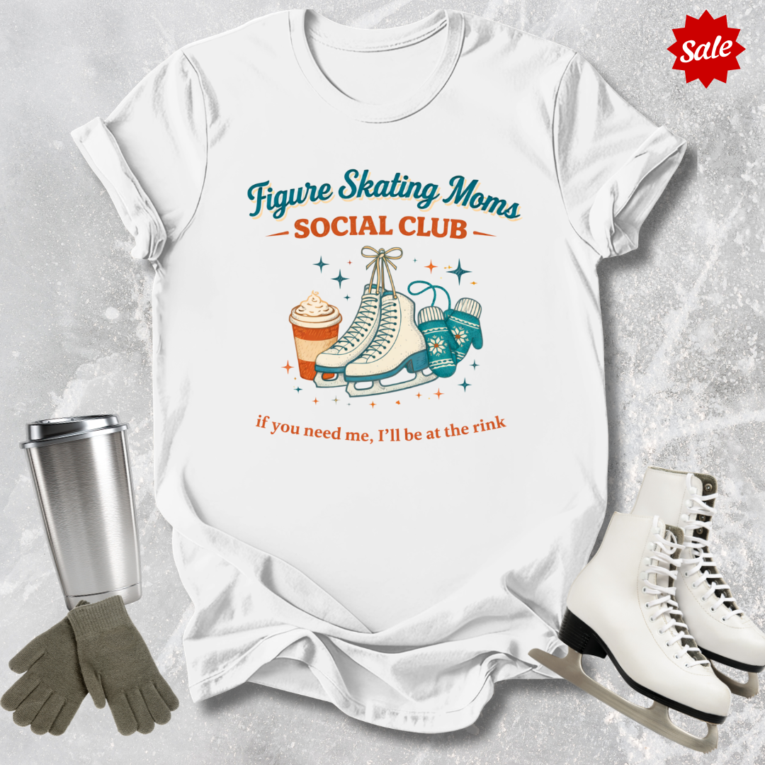 White t-shirt with figure skating-themed design, surrounded by ice skates, gloves, and a tumbler on a textured surface.
